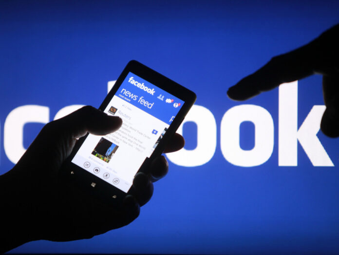 FILE PHOTO: Attendees walk past a Facebook logo during Facebook Inc's F8 developers conference in San Jose