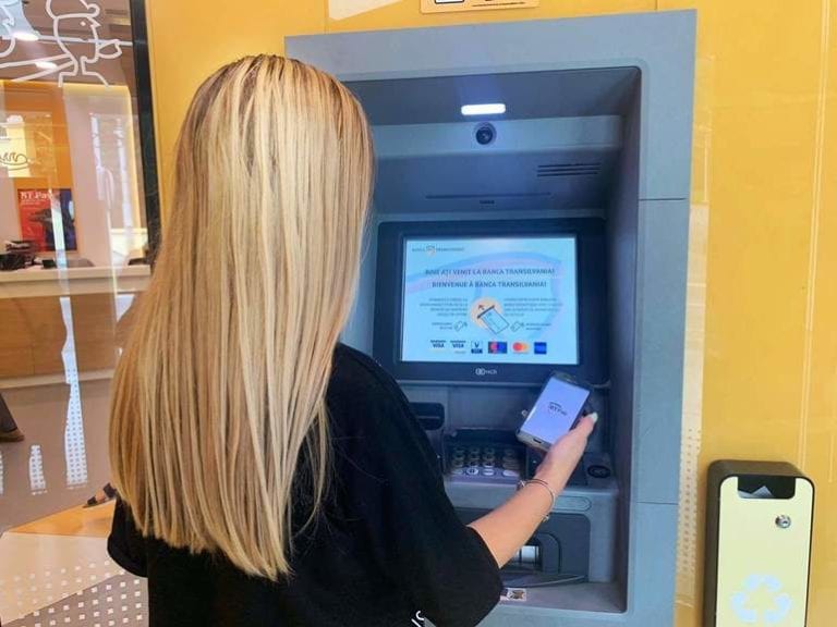 Premieră: Retrageri de numerar cu telefonul mobil, fără introducerea cardului, la bancomatele Băncii Transilvania